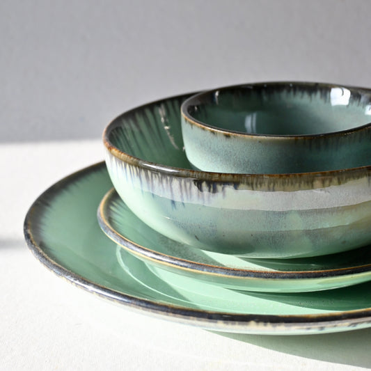Set of green ceramic plates and bowls on a light gray background from Saabi House