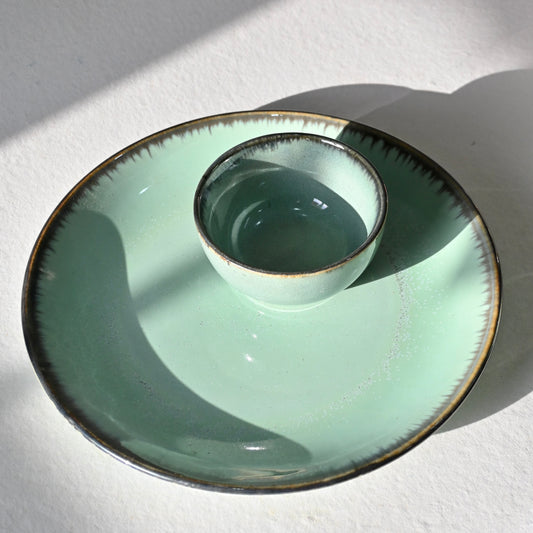 Green ceramic dish with a smaller bowl inside on a white surface