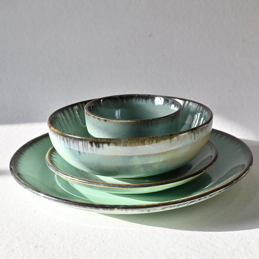 Set of green ceramic dishes on a white surface with a gray background from Saabi House