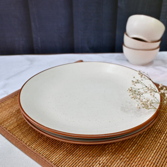 Set of ceramic plates with brown rim on a woven placemat