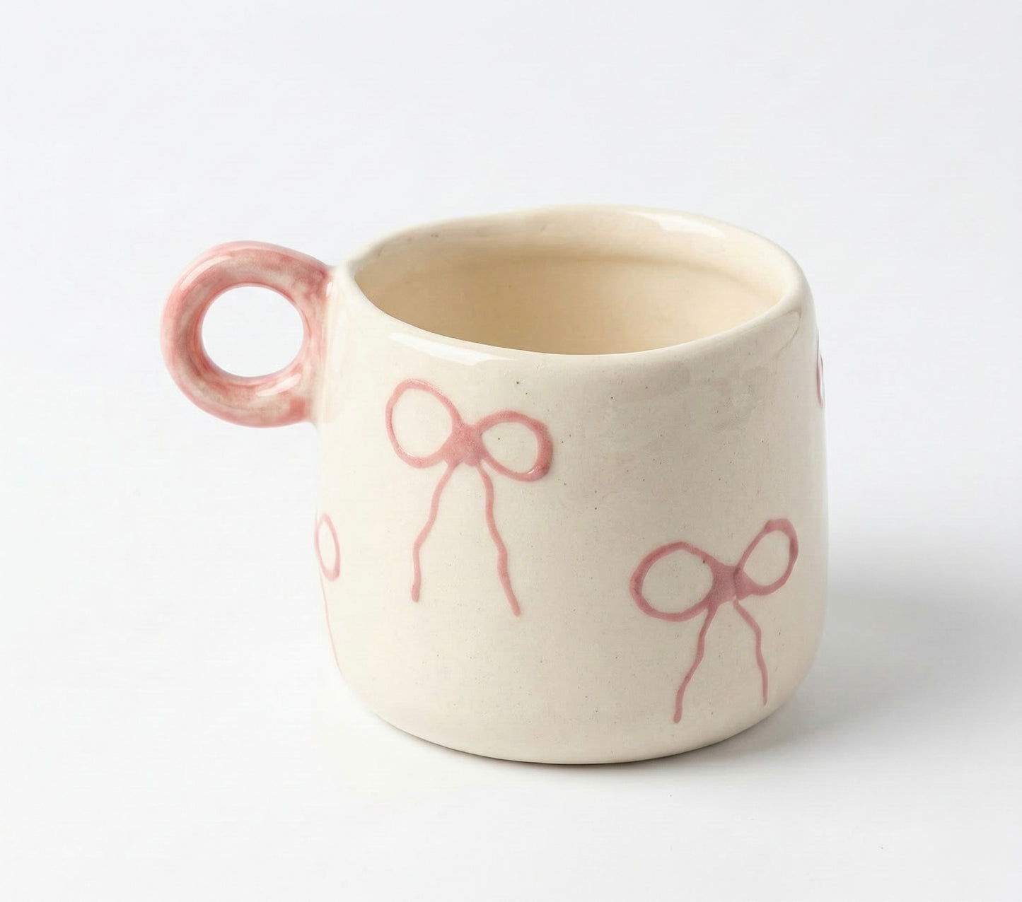 Ceramic mug with pink handles and bow designs on a white background