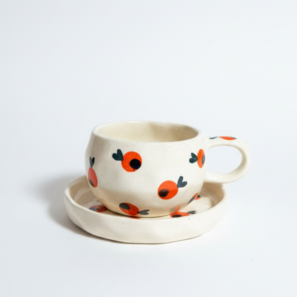 Ceramic cup and saucer with orange pattern on a light gray background from saabi house